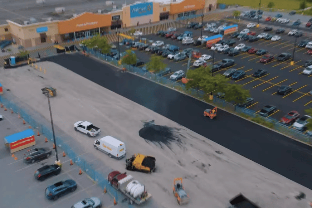 Paving project underway in a large retail parking lot with heavy machinery.